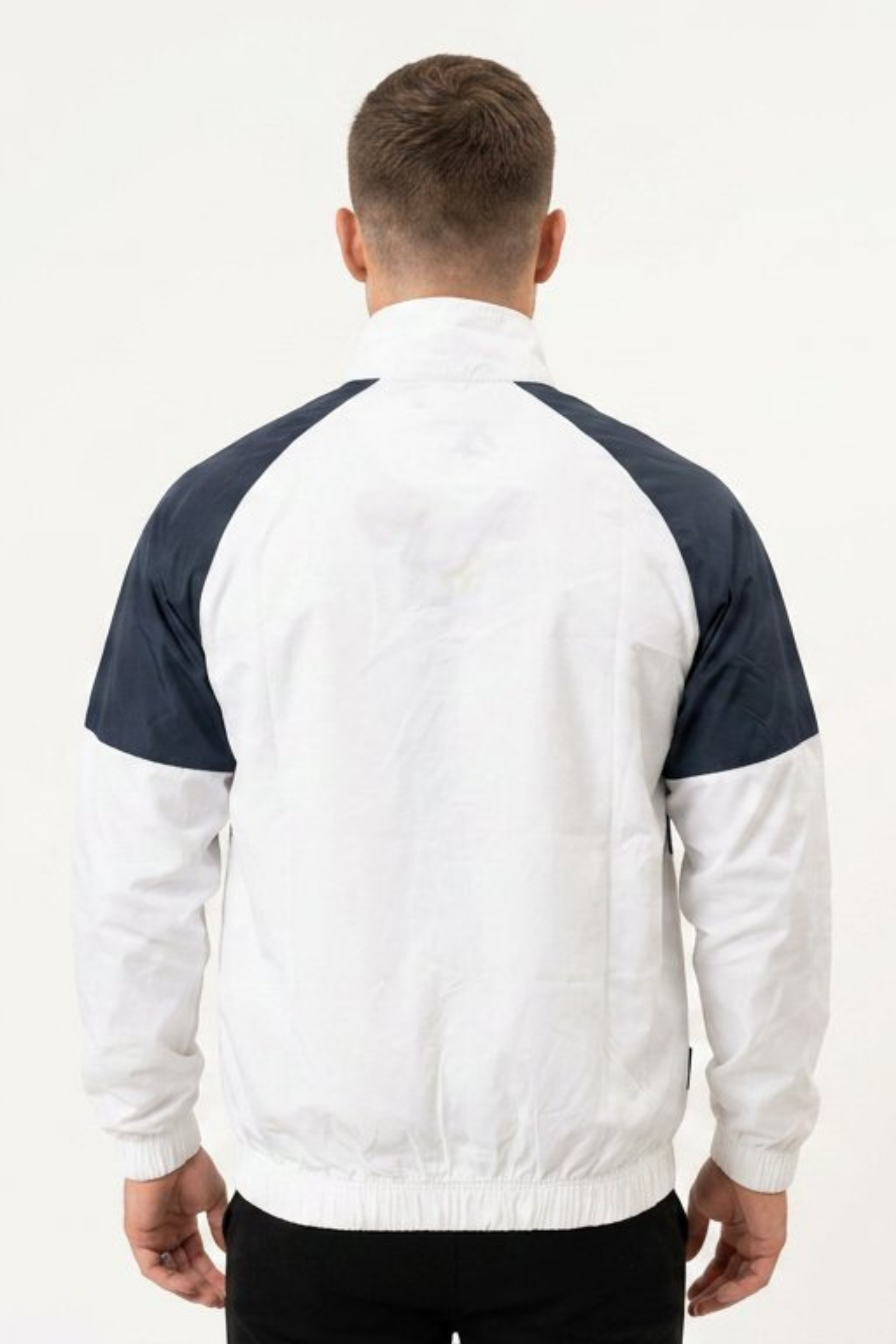 Back view of men’s navy and white two-tone windbreaker jacket with elasticated hem