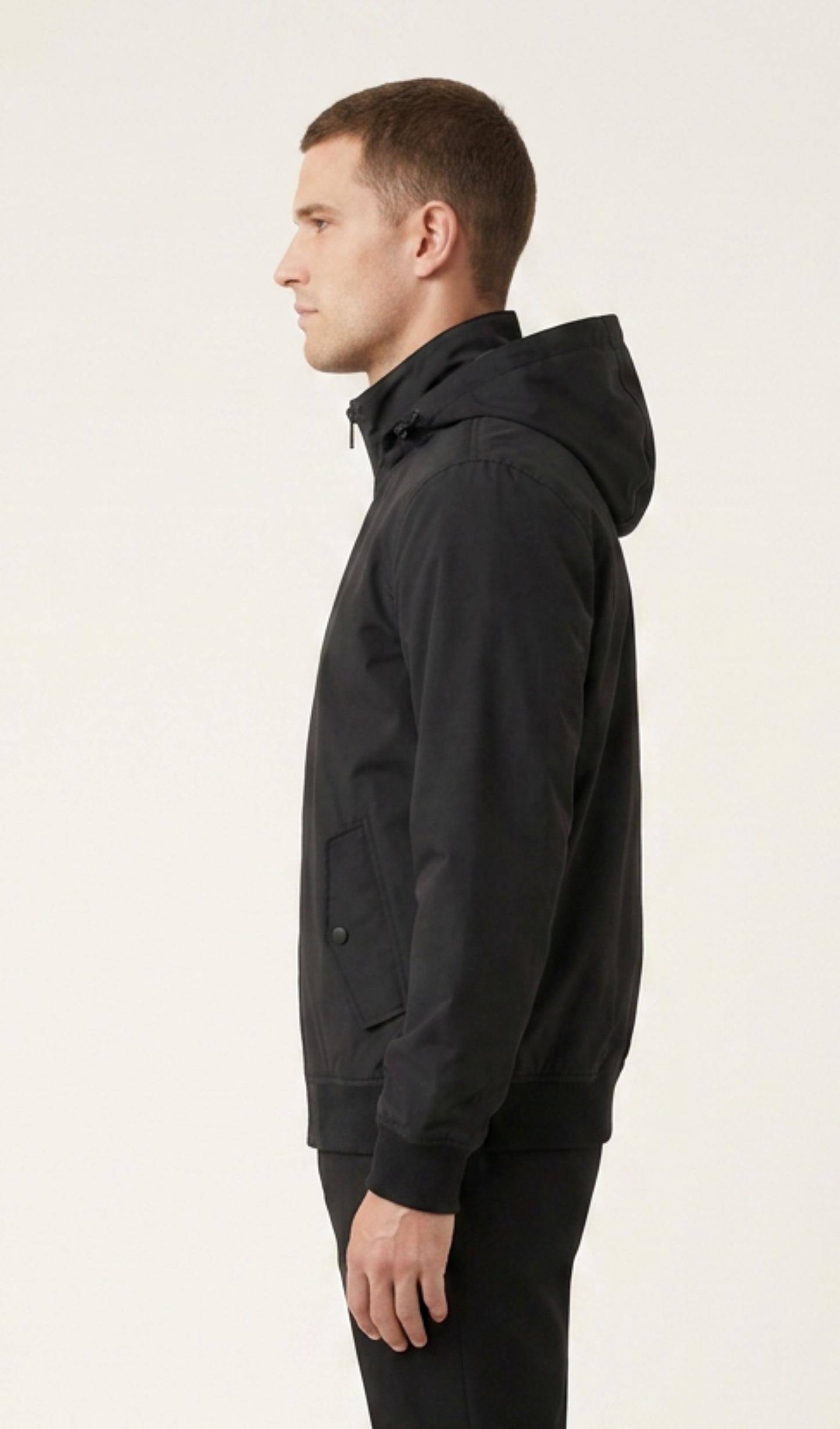 Side view of men’s solid-black lightweight windbreaker with attached hood and ribbed cuff